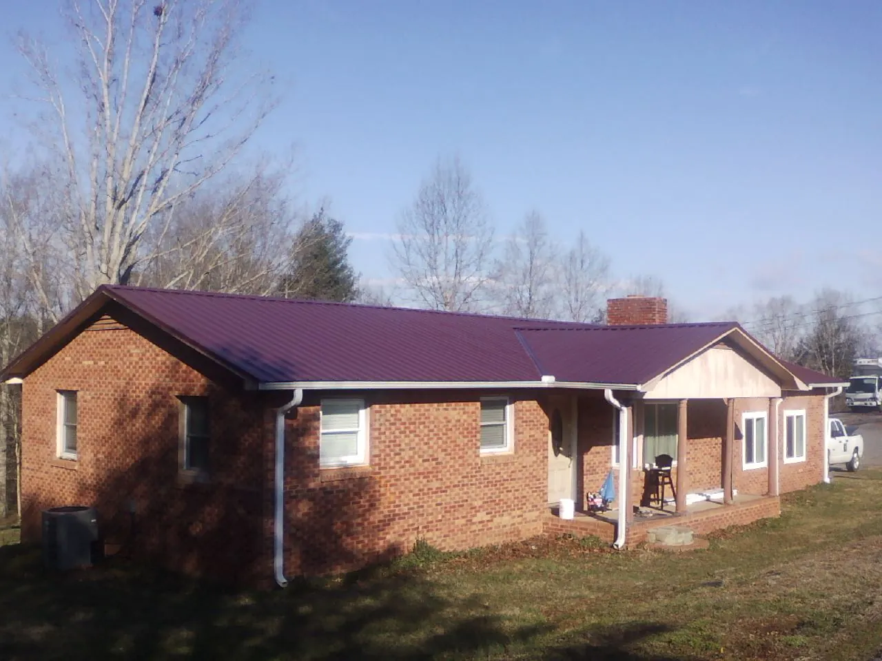 Burgundy metal roof on a brick ranch home with a new addition in Igo