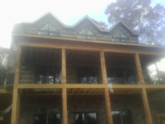 Dormers and porch framing on a large log home under construction — Roof Coating work by our crew in Igo